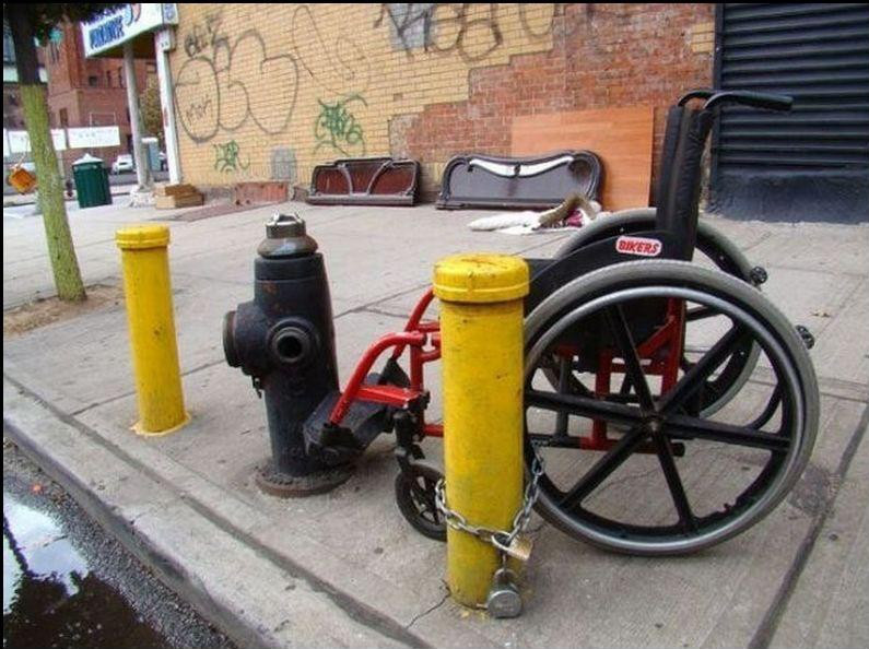 Fauteuil roulant parque et cadenasse a une borne d'incendie, dans la rue